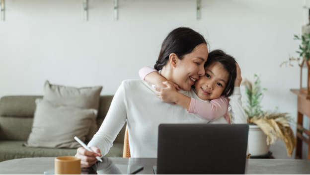 Daughter hugging Mum at home office desk